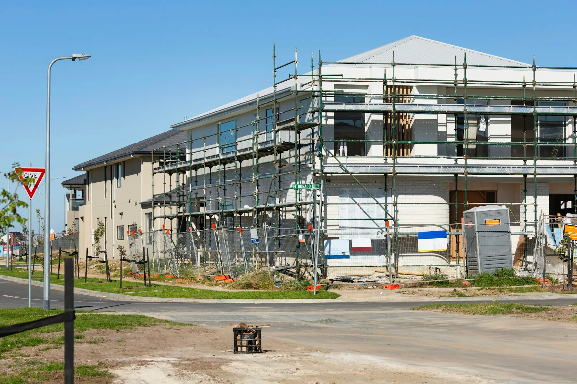 Steel scaffolding around a residential building under a blue sky