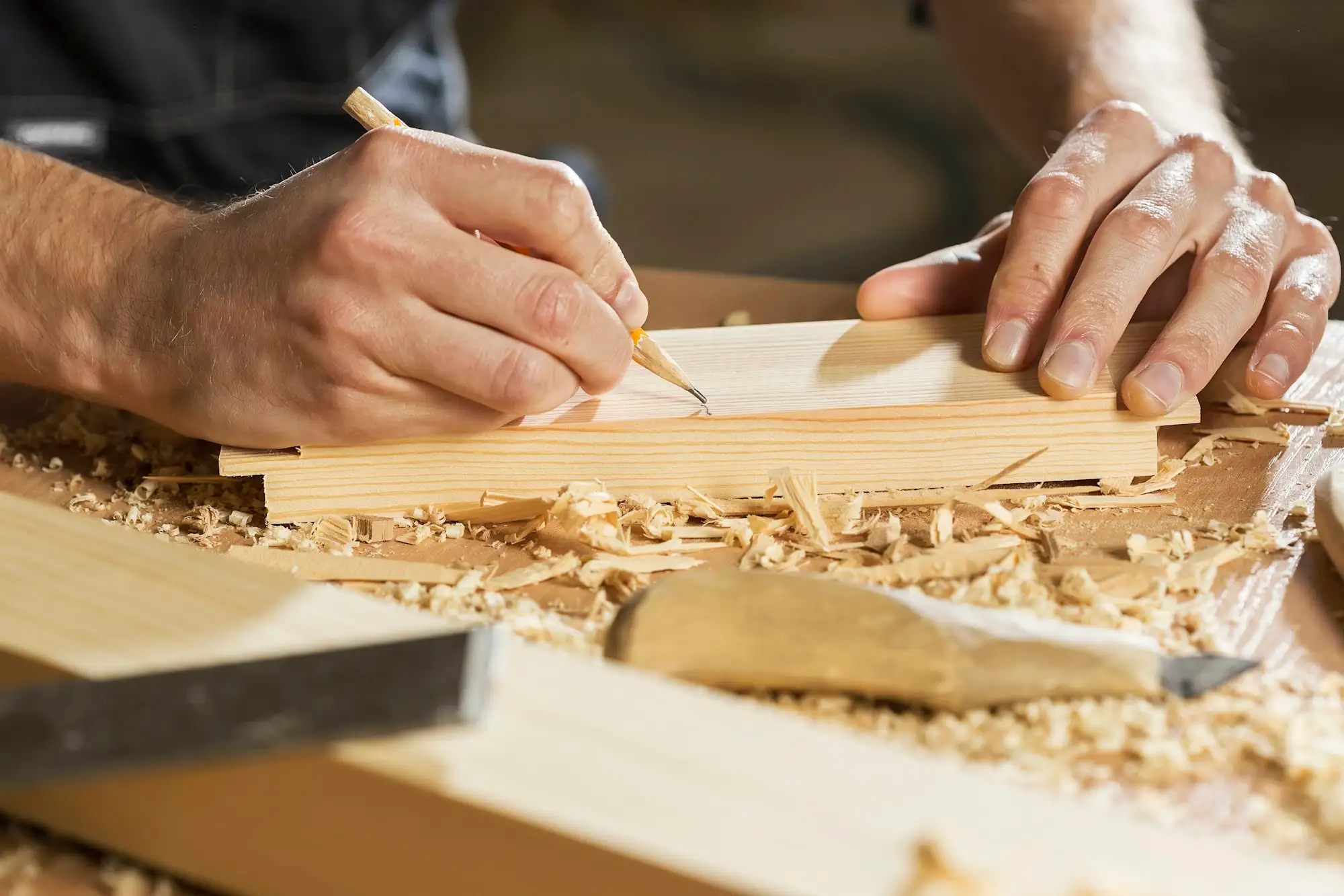 Carpenter marking a length of timber with a pencil