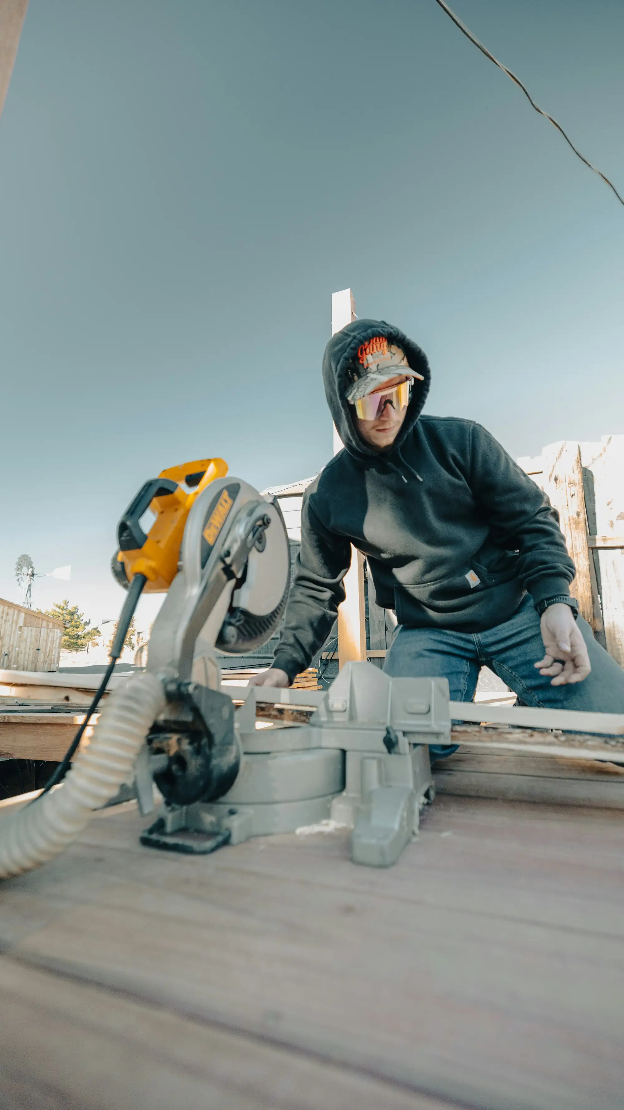 Carpenter cutting decking boards with a mitre saw on an Australian job site