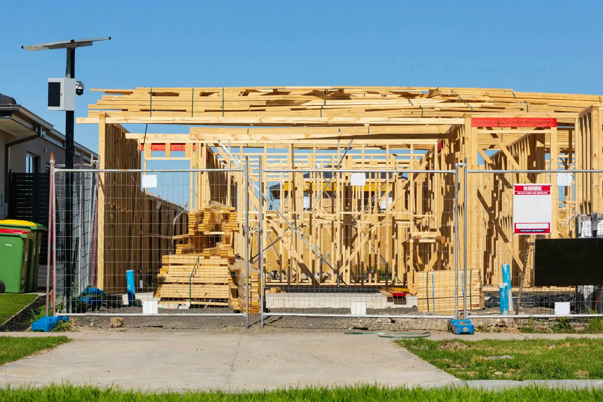 Stalled house frame behind temporary site fencing in Australia