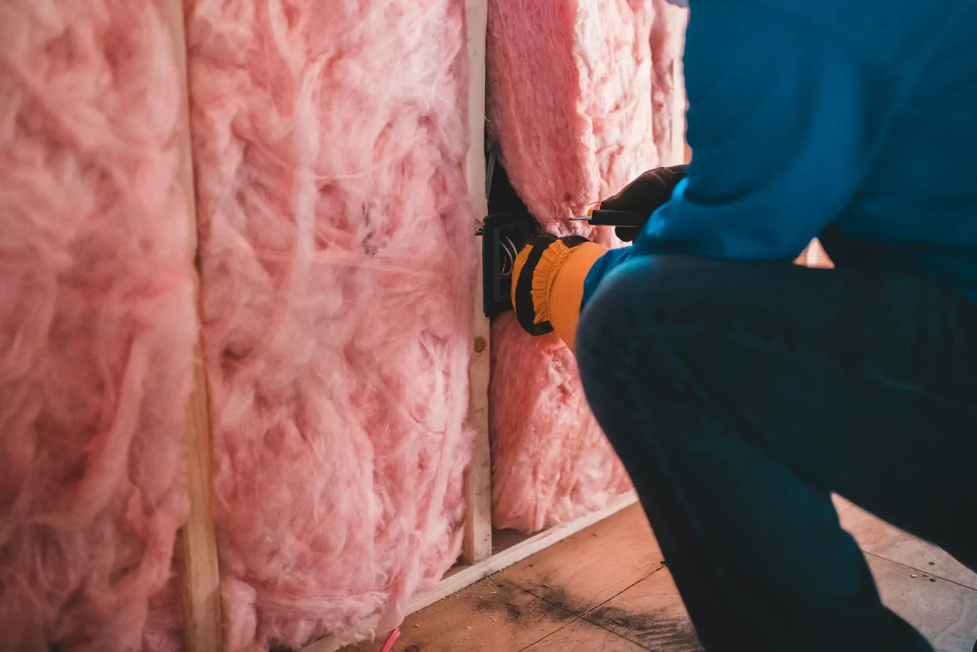 Installer fitting insulation batts between timber wall studs