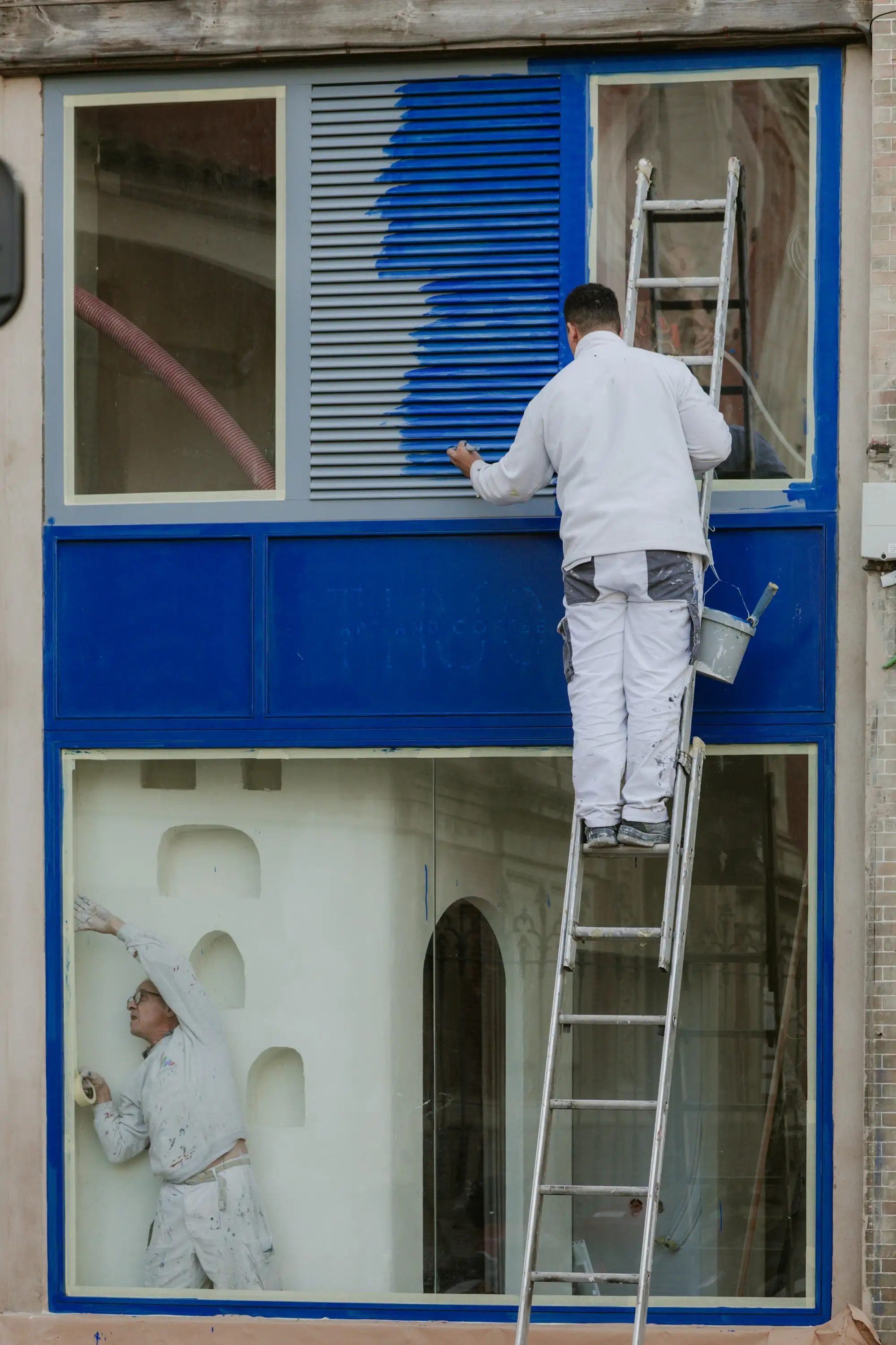 Painter on a ladder painting around a window on an Australian home